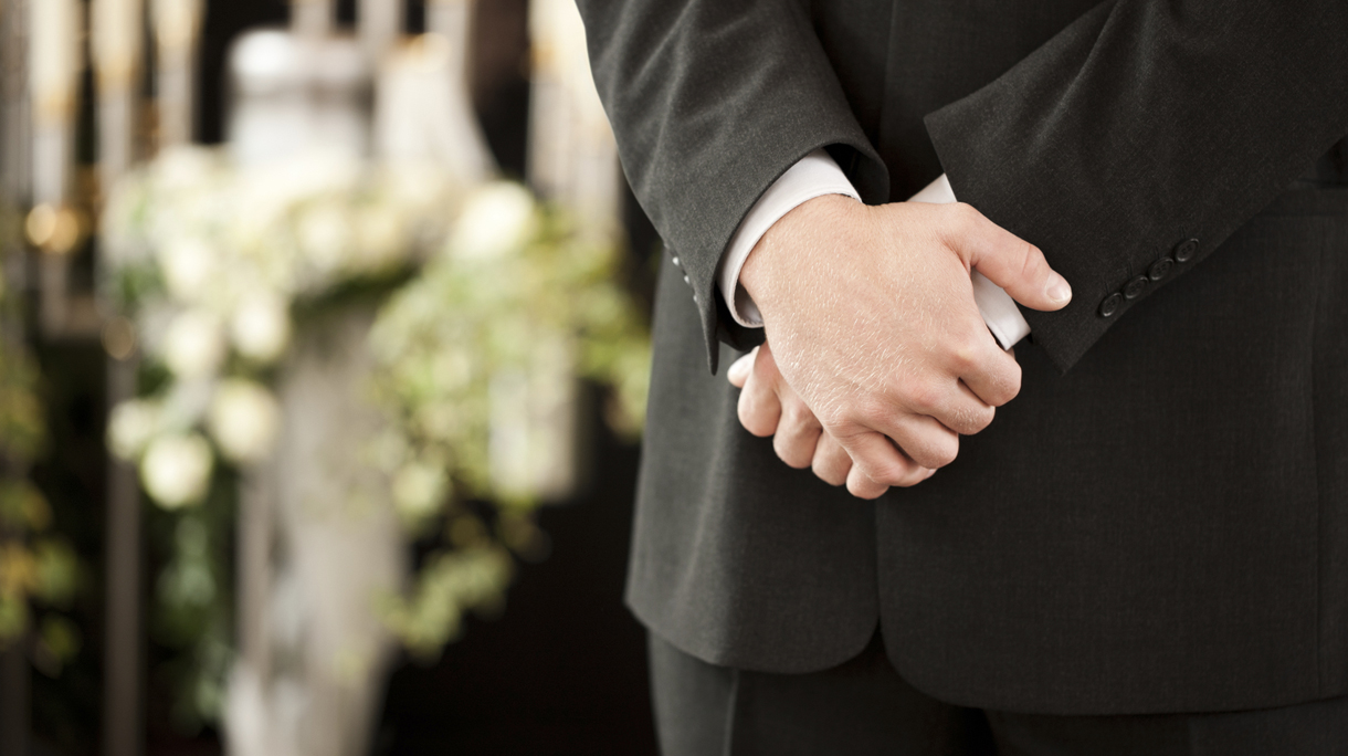 man or mortician at funeral mourning
