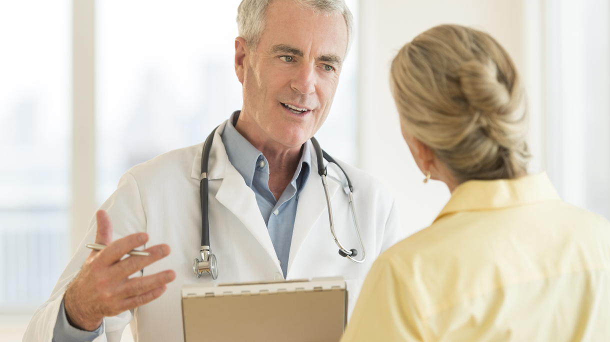 Doctor Explaining Report To Patient In Hospital