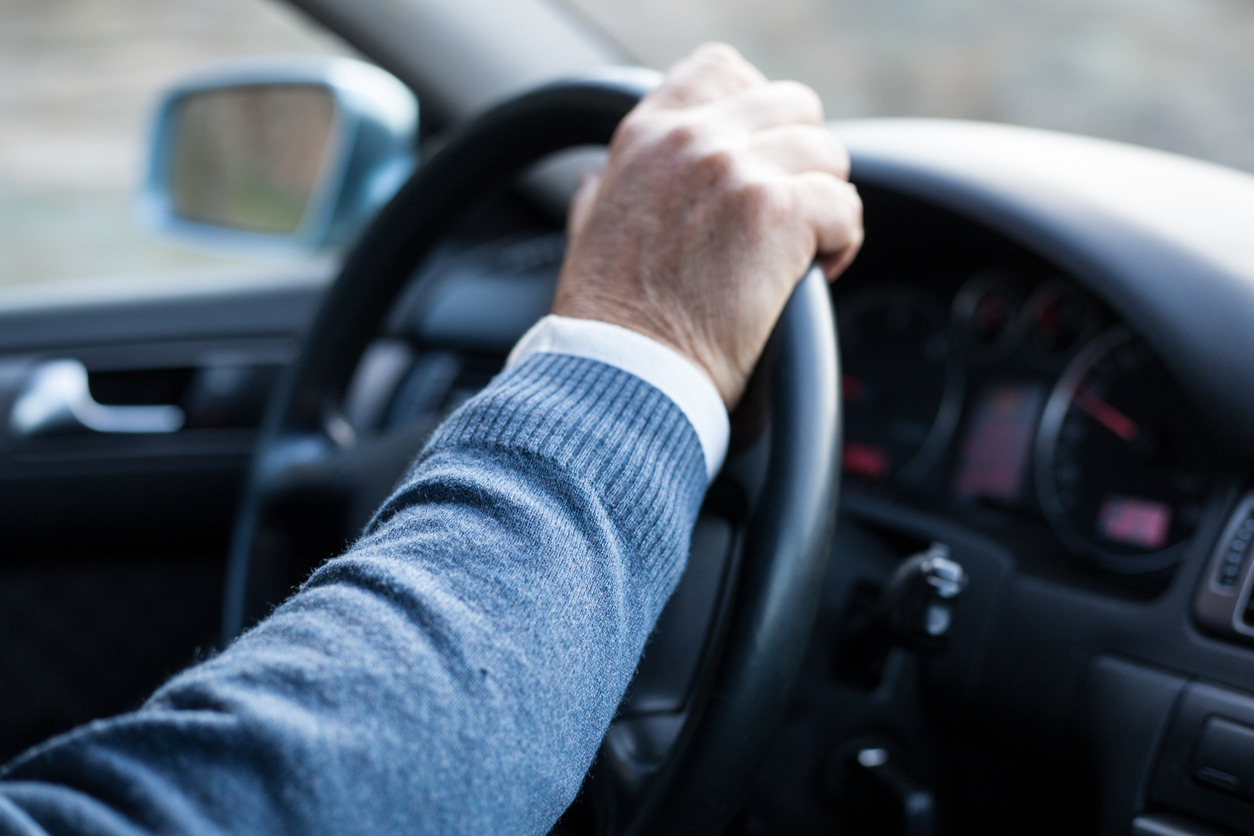 Man hand holding steering wheel in motion while drives.
