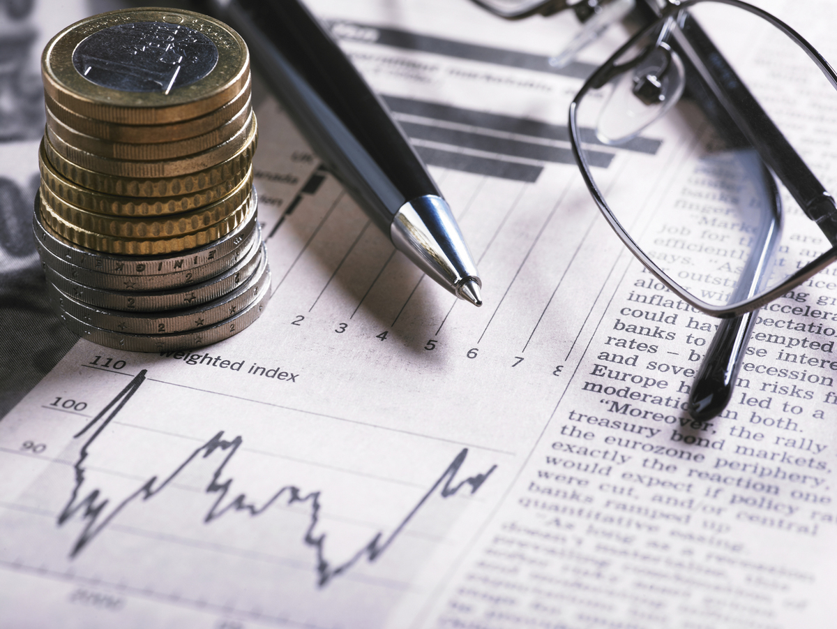 A financial chart with coins, glasses and pen
