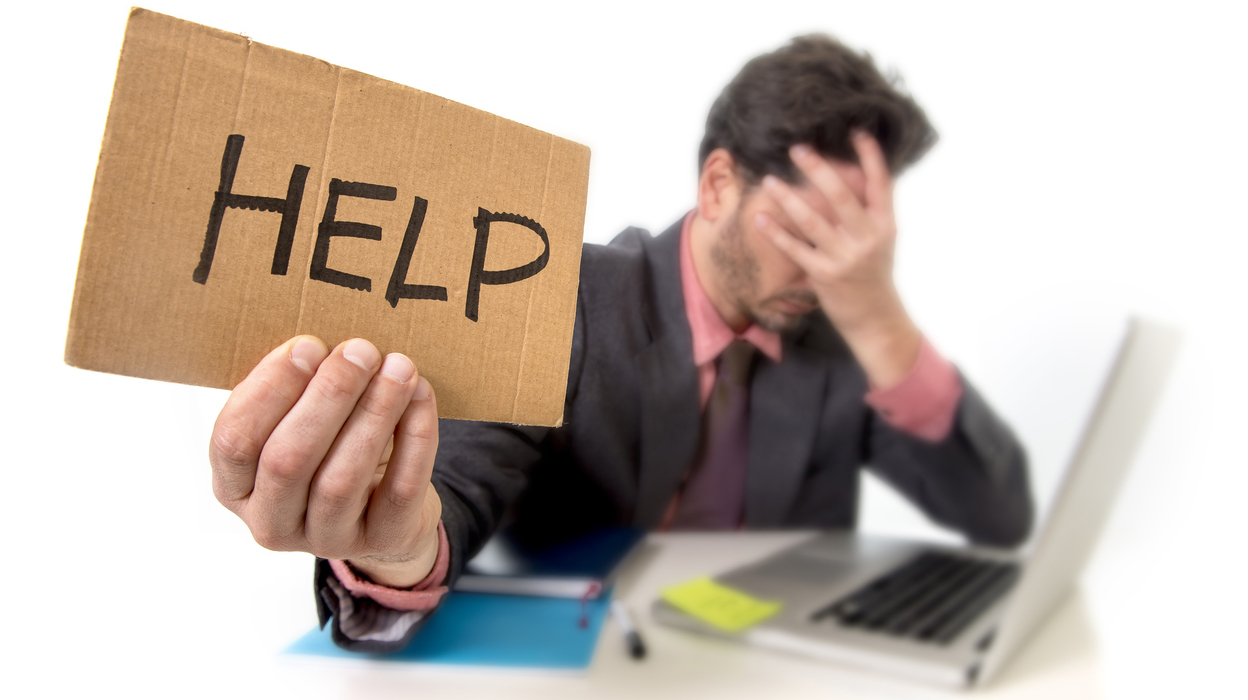 depressed businessman at office working on computer asking for help