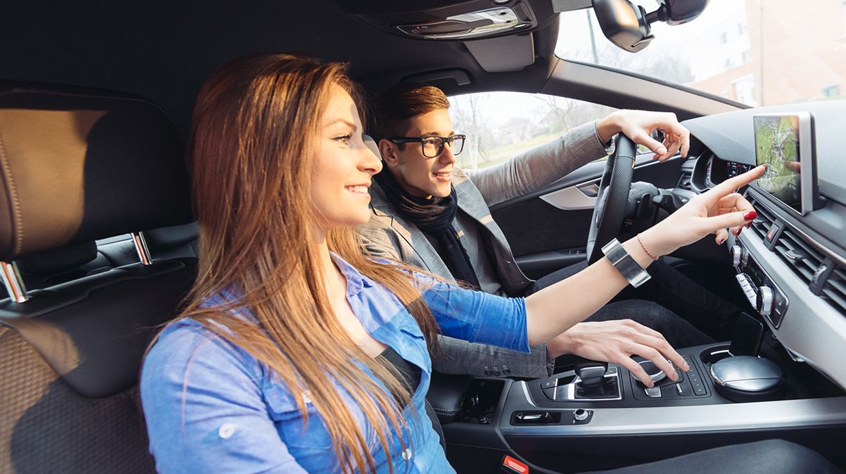 Portrait of attractive young couple driving luxury car in city