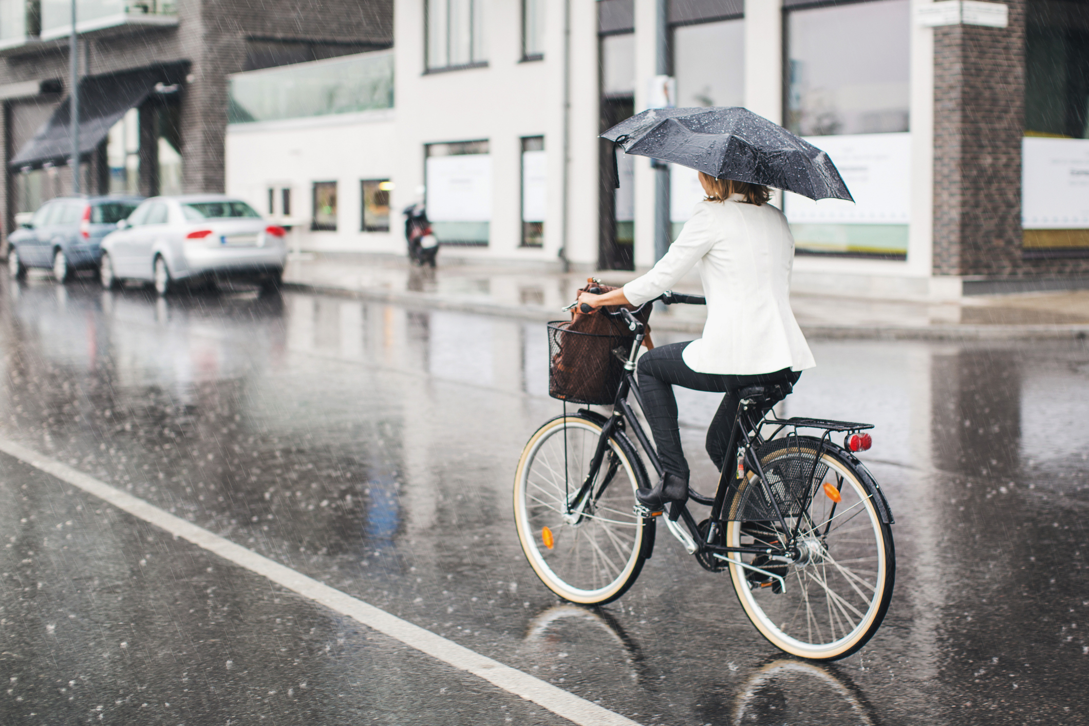 Fietsen in de stad terwijl het regent met paraplu