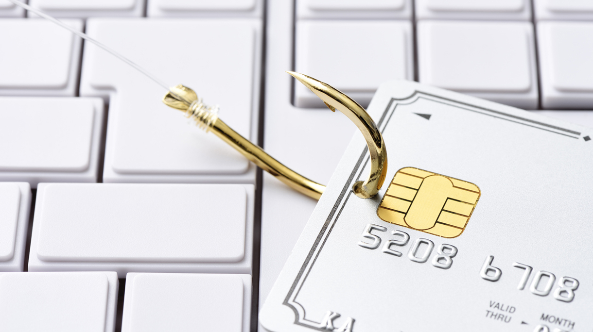 Close-up of credit card with fishing hook on computer keyboard