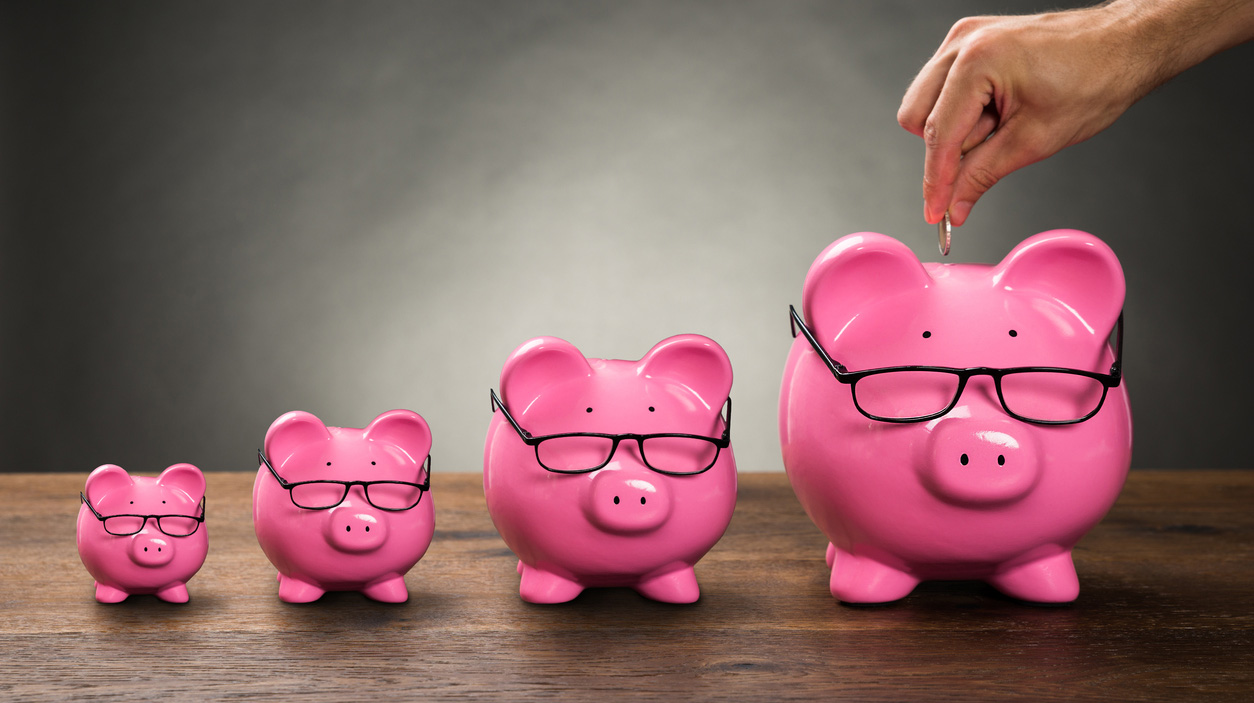 Person Hand Inserting Coin In Piggybank