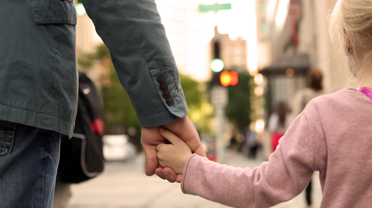 father holding  the daughter/ child  hand  behind  the traffic lights