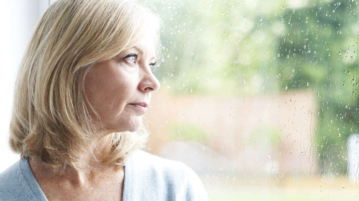 Sad Mature Woman Suffering From Agoraphobia Looking Out Of Windo