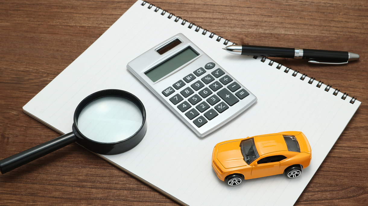 Toy car, magnifying glass, calculator, pen and notebook.