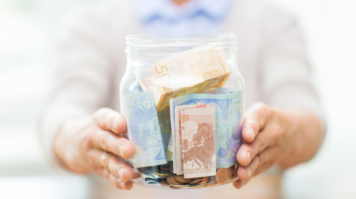 close up of senior woman with money in glass jar