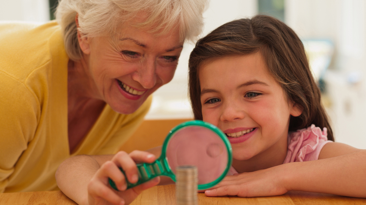 Grandmother and granddaughter looking at coins with magnifying glass