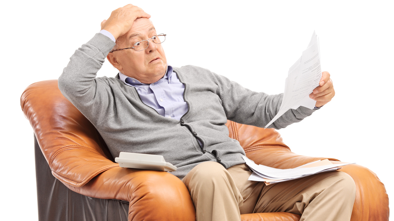 Shocked senior man looking at his bills in disbelief