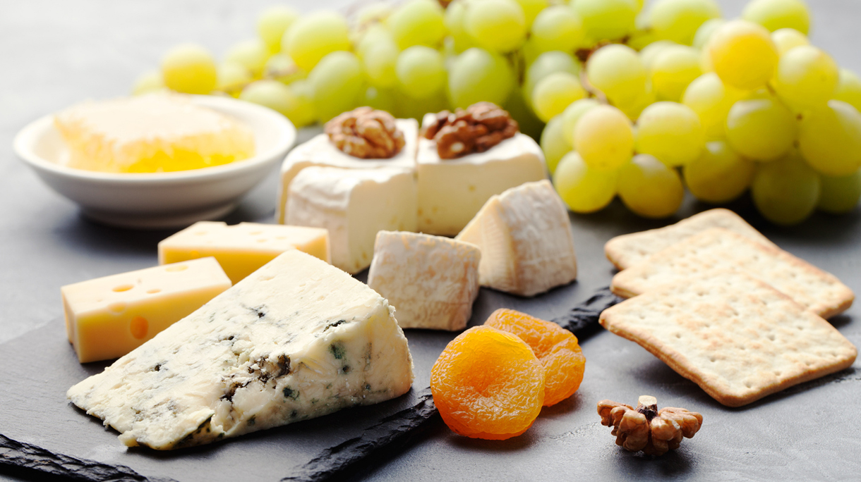 Glass of white wine and assorted cheese with grape