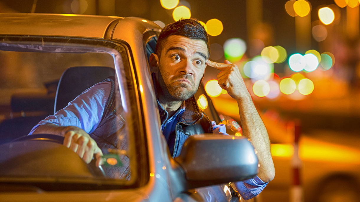 Young man driving car at night angry to traffic