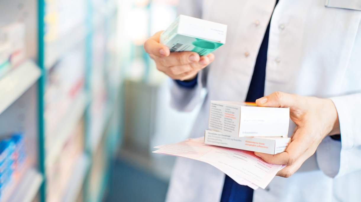 Pharmacist’s hands taking medicines from shelf