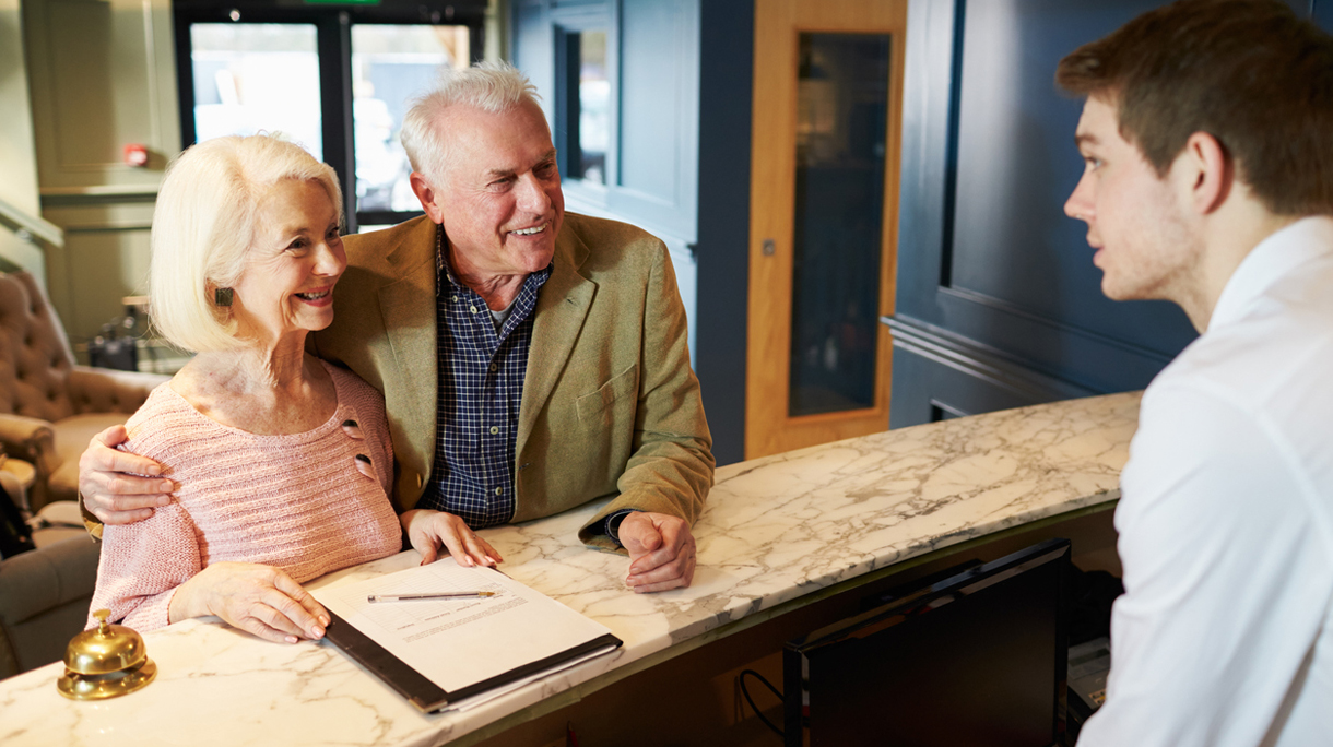 Senior Couple Checking In At Hotel Reception