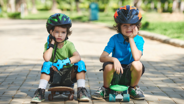 Two little skateboarders in summer park