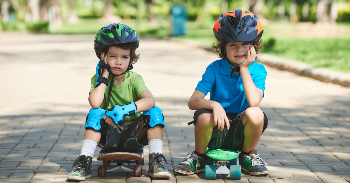 Two little skateboarders in summer park