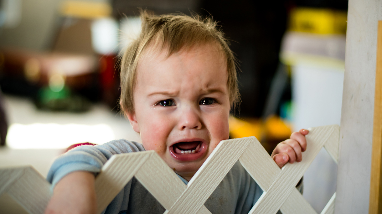 Crying baby behind a gate