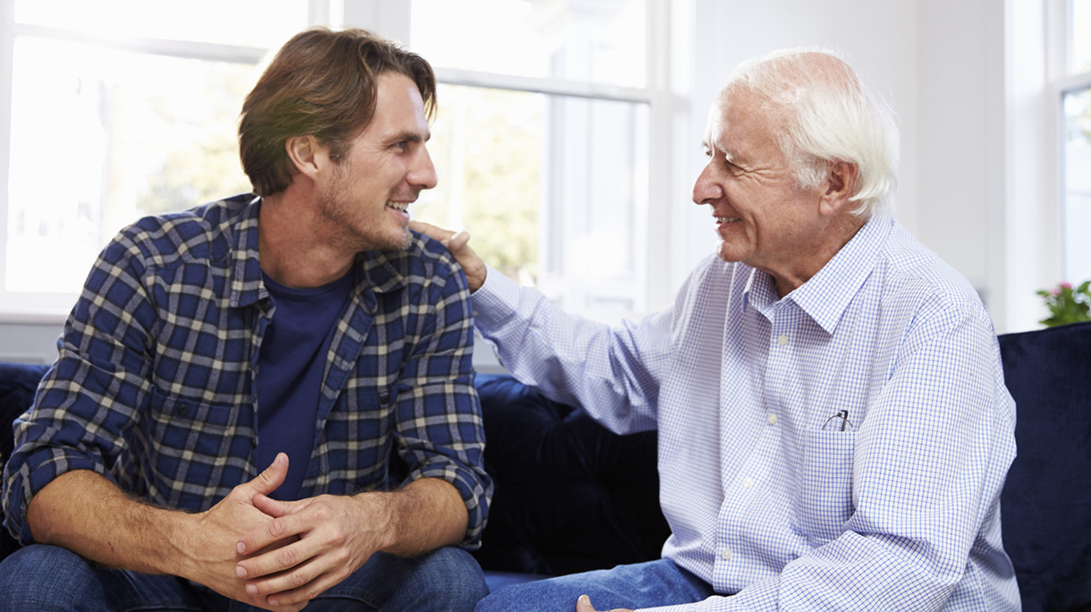 Adult Son Sitting On Sofa And Talking To Father At