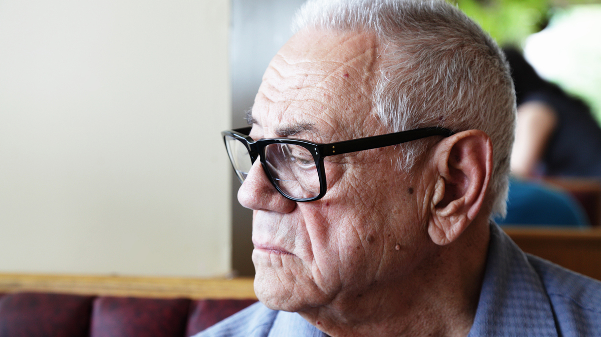 Senior Man With Dementia Sitting Alone in Restaurant Looking Down