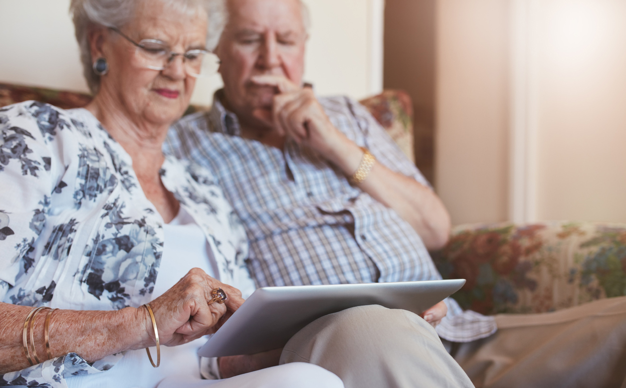 Elderly couple at home using digital tablet