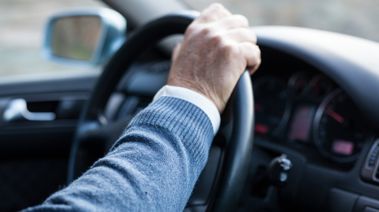 Man hand holding steering wheel in motion while drives.