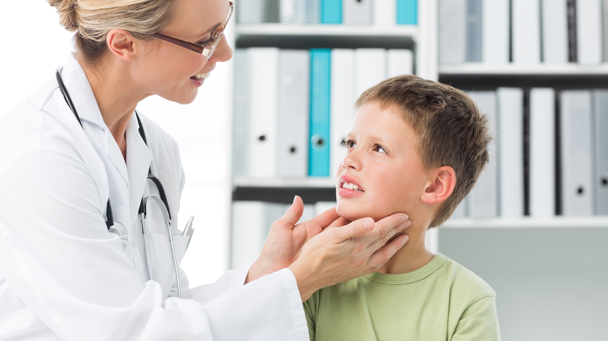 Pediatrician examining thyroid gland of boy