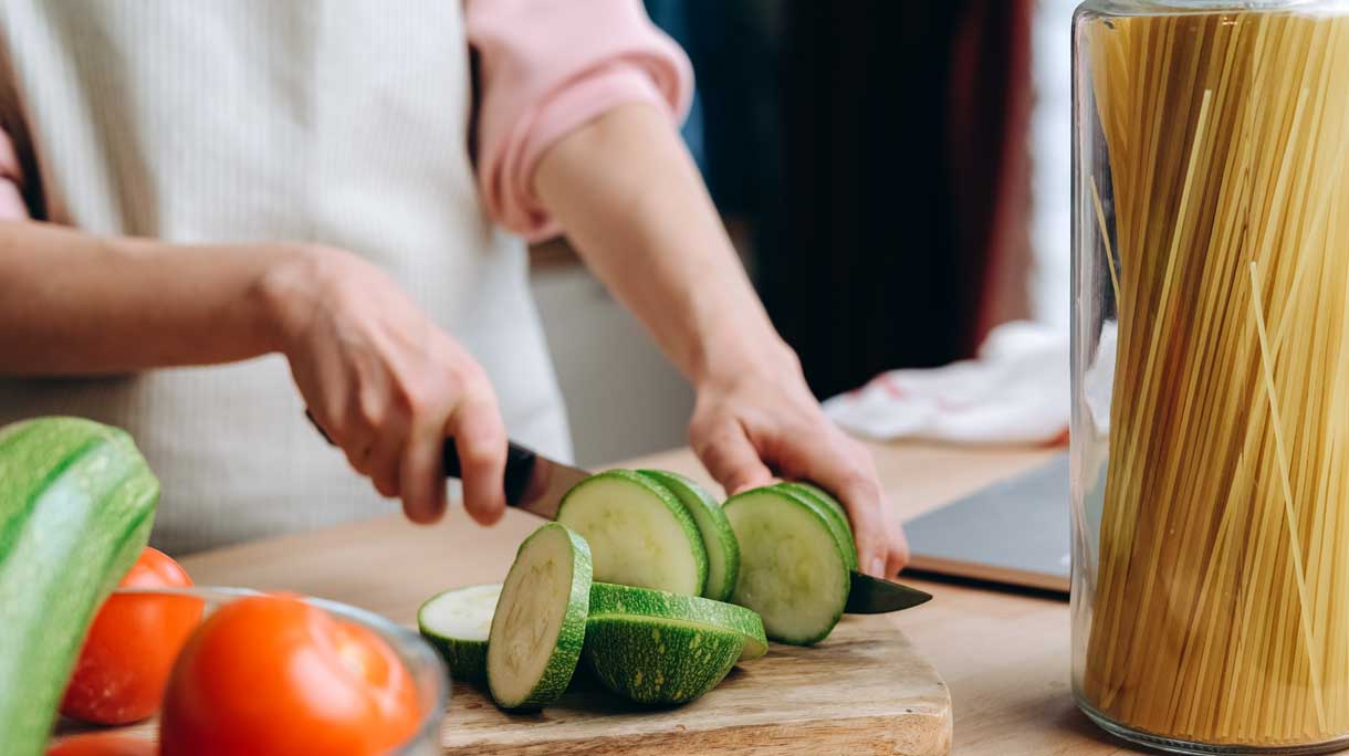Een vrouw is courgette aan het snijden op een snijplank