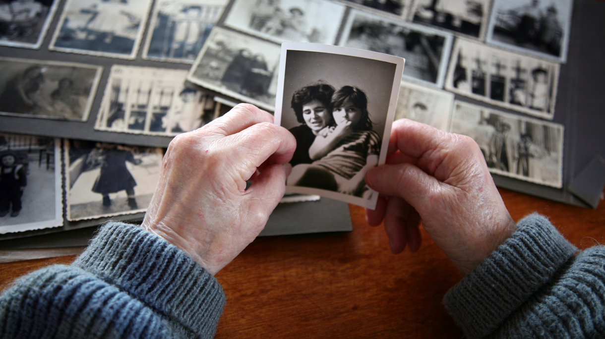 Elderly hands looking at old photos of self and family