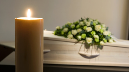 Burning candle in front of coffin