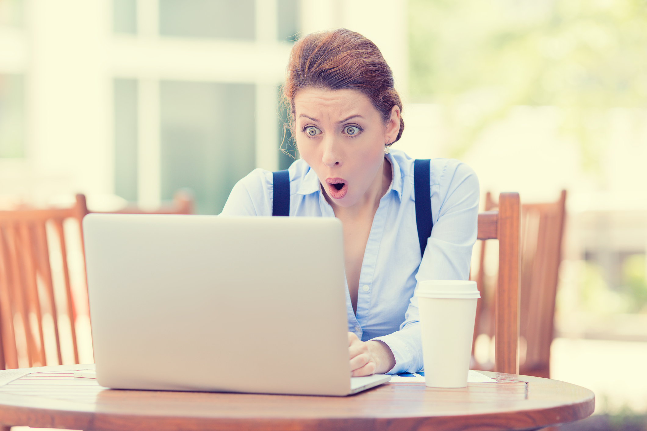 young business woman using laptop looking at computer screen blown away in stupor sitting outside