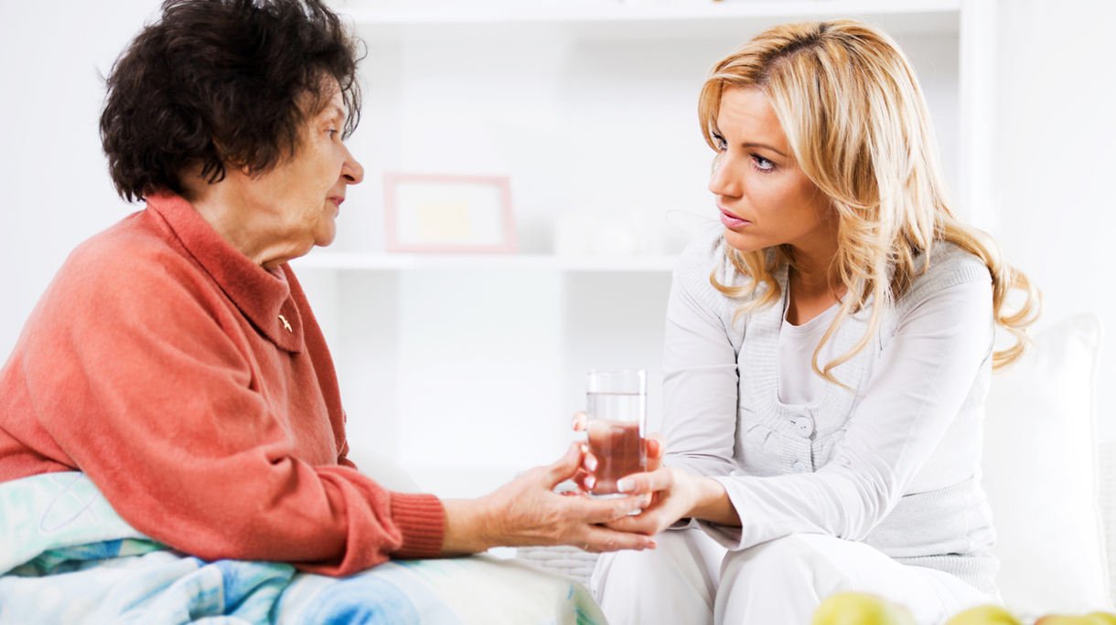 Home caregiver giving a senior woman glass of water