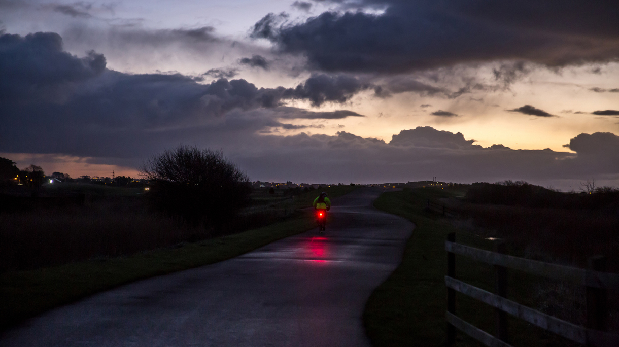 Cyclist travelling on cycle path at daybreak