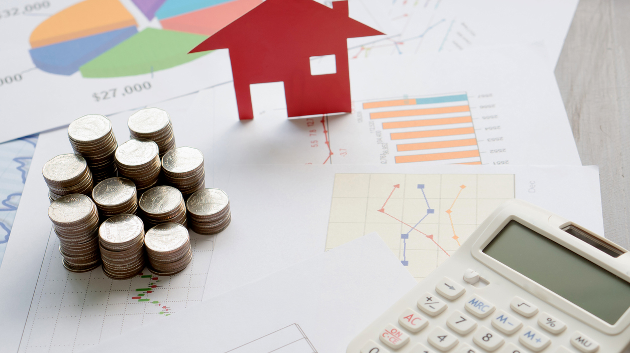 With House Model And Stack Of Coins On Desk