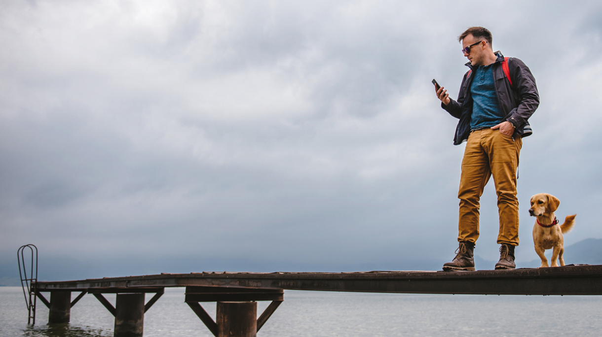 Man standing on dock and using smart phone