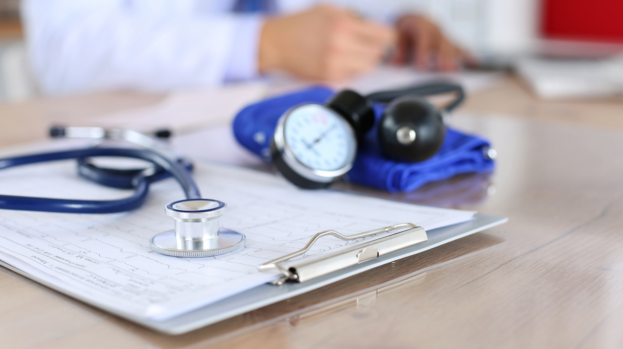 Medical stethoscope lying on cardiogram chart closeup