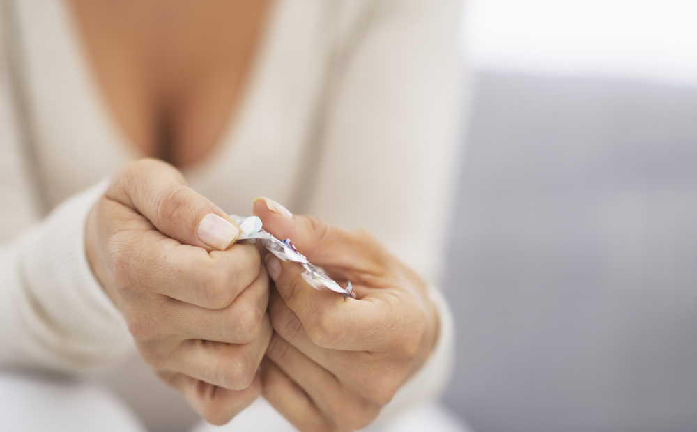 Closeup on hand pushing pill out of blister package