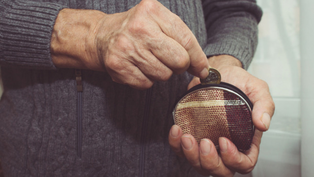 An elderly man puts a coin in an empty wallet. Poverty in retirement concept. Special toning
