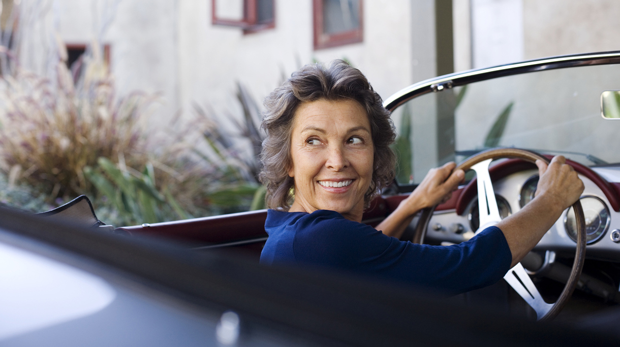 Woman sitting in convertible car smiling over her shoulder