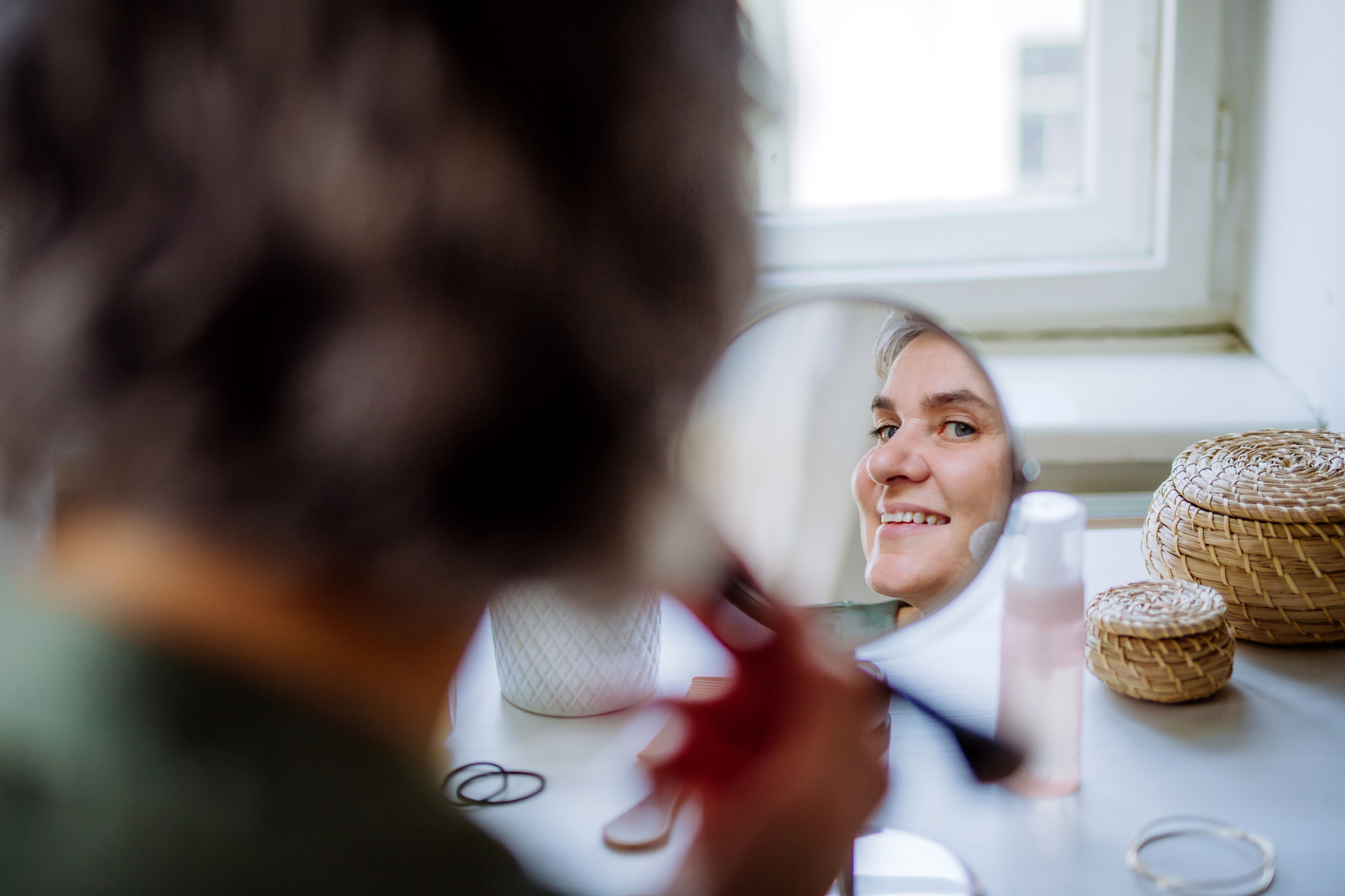 Vrouw maakt haar gezicht op in de spiegel