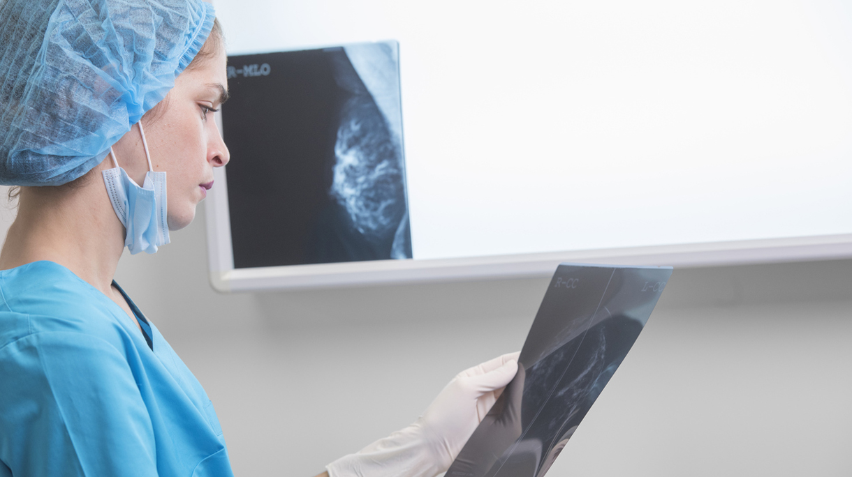 woman doctor or nurse in surgery outfit is holding a mammogram in front of x-ray illuminator