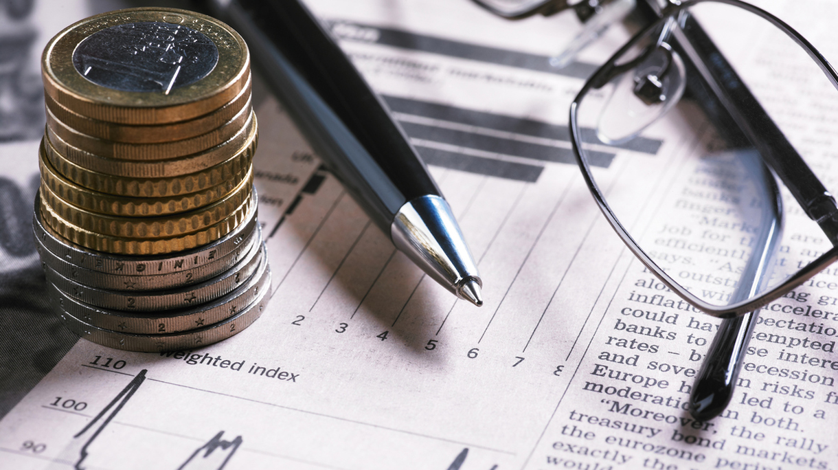 A financial chart with coins, glasses and pen