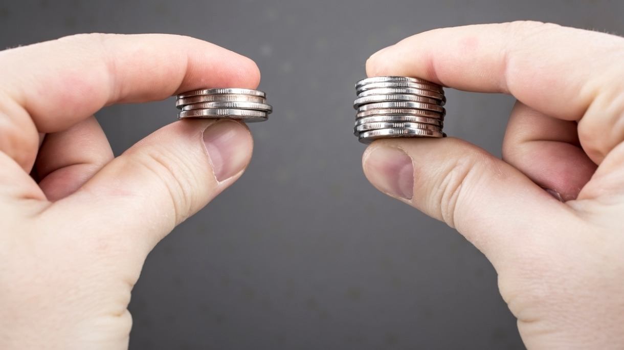 hands-compare-two-piles-of-coins-of-different-sizes-picture-id516457744