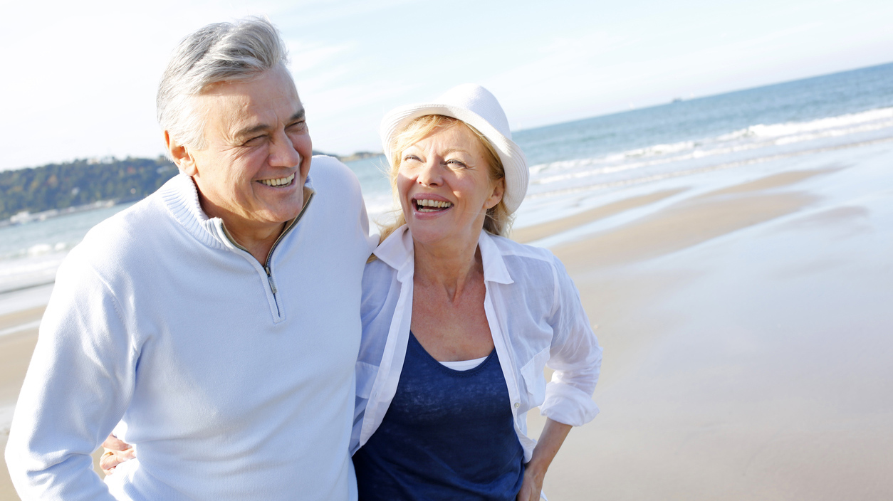 Happy senior couple walking on beach