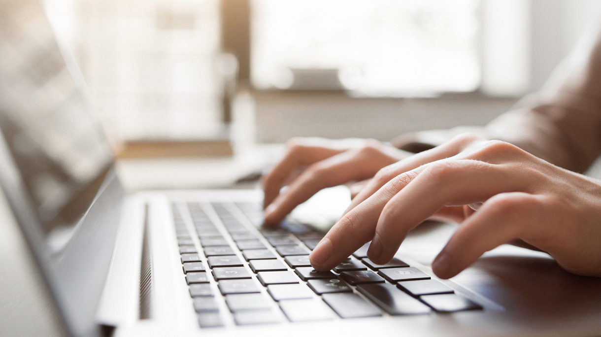 Typing on laptop closeup, chatting in Facebook