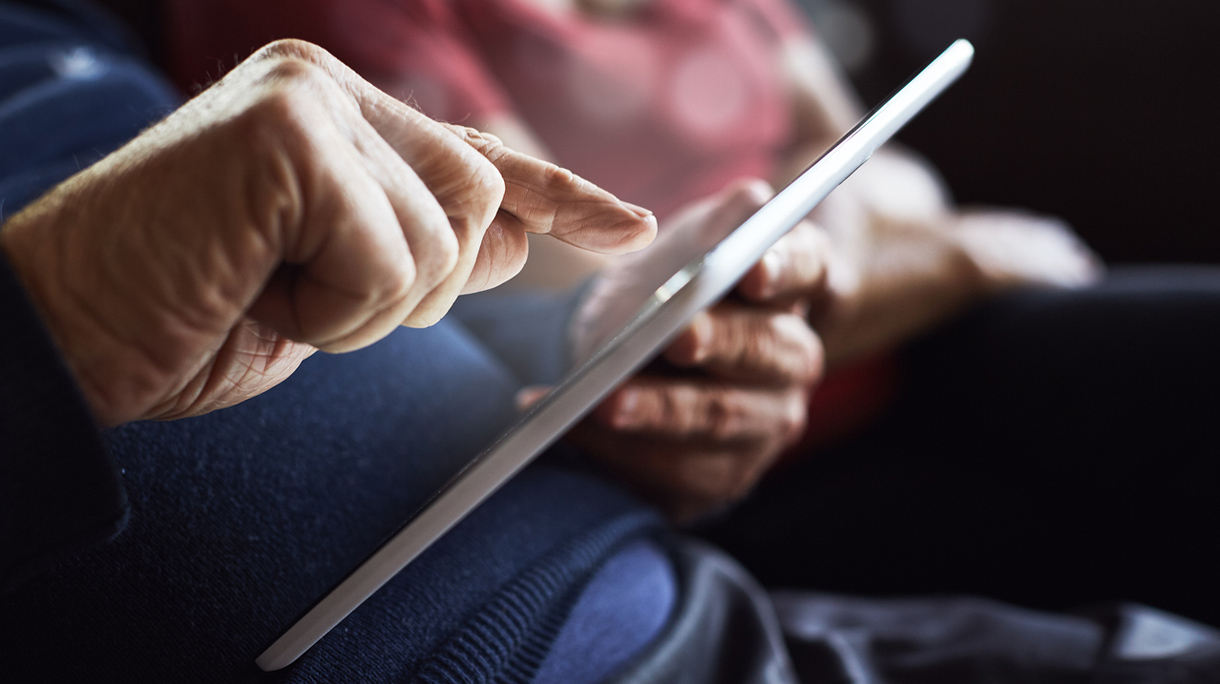Senior man’s hands tapping tablet screen
