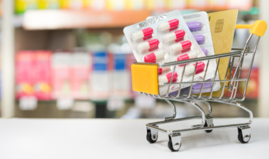 Shopping trolley with medical pills and card with blurred pharmacy shop