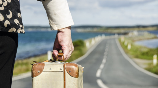 Senior Woman travelling with her suitcase on the road going for retirement