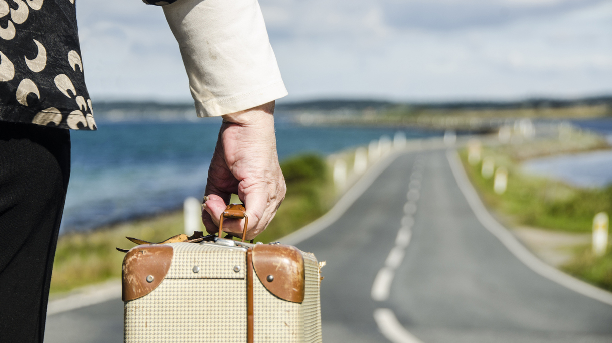 Senior Woman travelling with her suitcase on the road going for retirement