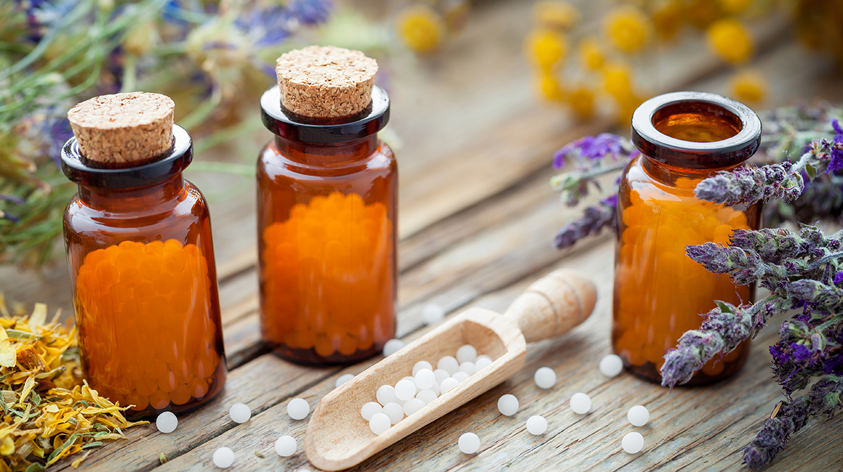 Bottles of homeopathic globules and healing herbs. Homeopathy concept.